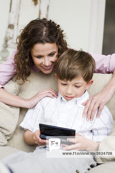 Frau schaut ihrem Sohn beim Videospielen zu.