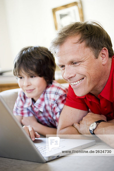 Vater und Sohn lächeln in den Laptop
