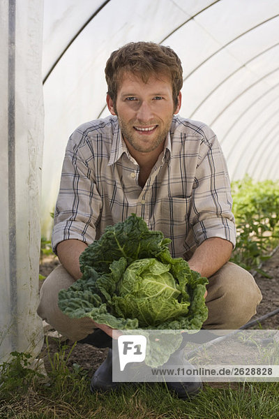 Man in greenhouse holding cabbage  portrait