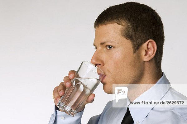 Geschäftsmann trinkt ein Glas Wasser.