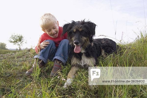 Kleiner Junge (3-4) spielt mit Hund
