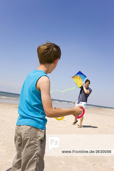 Deutschland  Ostsee  Vater mit Sohn (8-9) beim Drachenfliegen am Strand