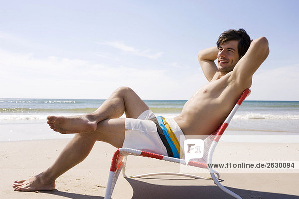 Germany  Baltic sea  Young man relaxing in chair on beach  portrait