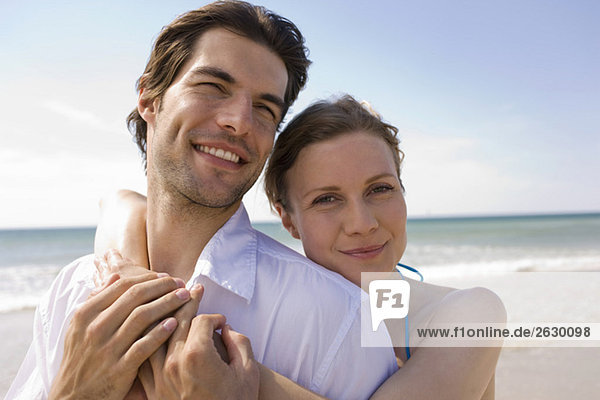 Germany  Baltic sea  Young couple embracing on beach  smiling  portrait