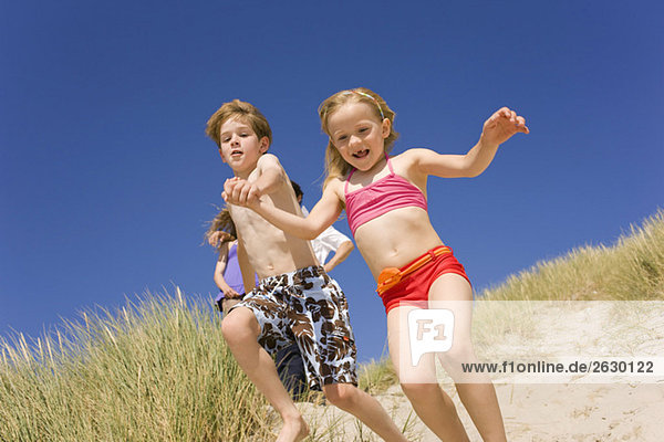 Deutschland  Ostsee  Junge (8-9) und Mädchen (6-7) springen die Stranddüne hinunter.