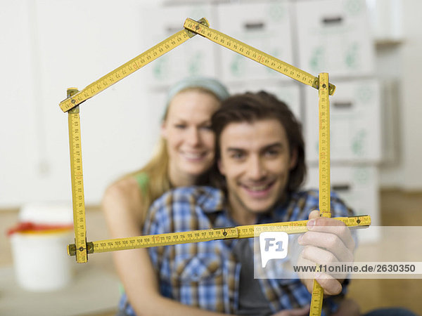 Young couple making house shape with folding rule  portrait