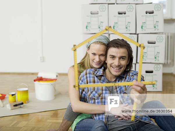 Junges Paar macht Hausform mit Zollstock  Portrait