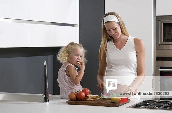 Pregnant mother and daughter (3-4) in the kitchen