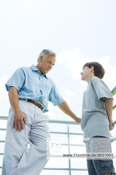 Großvater und Enkel stehen am Geländer  schauen sich an  Blick in den niedrigen Winkel