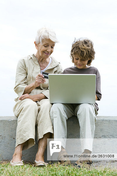 Großmutter und Enkel mit Laptop im Freien  Online-Shopping