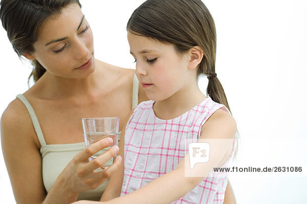 Mutter bietet der Tochter ein Glas Wasser an.
