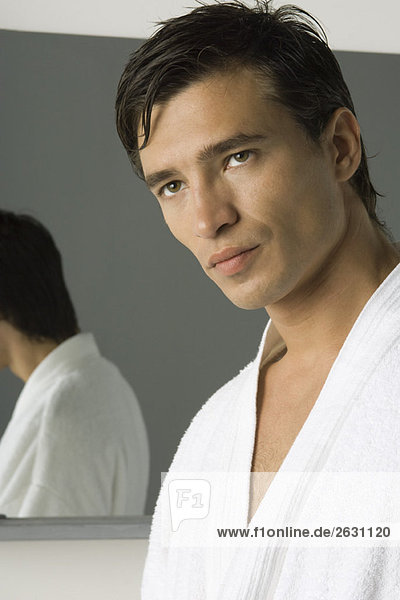 Man wearing bathrobe  looking away  mirror in background