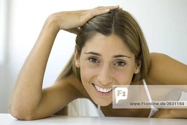 Frau lächelt Kamera  Hand auf Kopf  Porträt