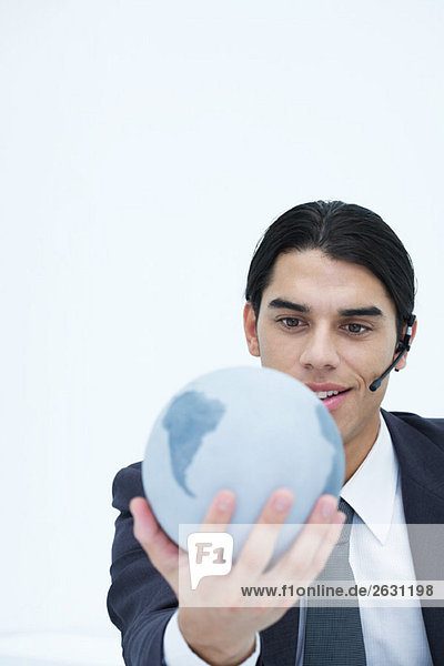 Young businessman holding globe  wearing headset