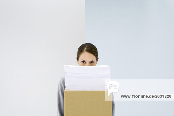 Frau blickt über den Papierstapel auf dem Karton