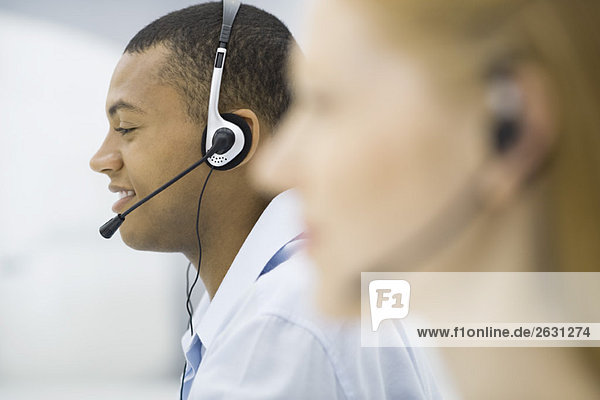 Telemarketers wearing headsets  profile  focus on background