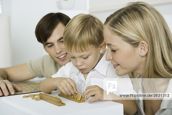 Parents watching as little boy arranges game pieces