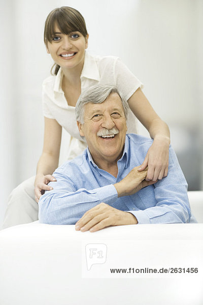 Älterer Mann und erwachsene Tochter  Händchen haltend  lächelnd vor der Kamera  Porträt