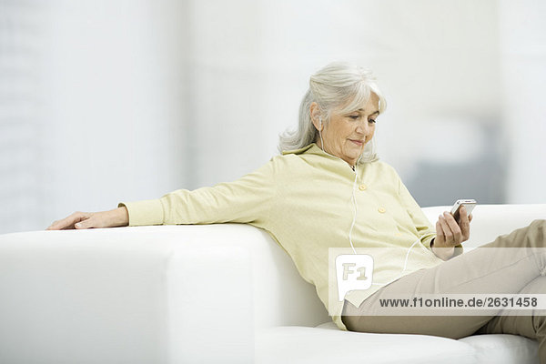 Seniorenfrau hört MP3-Player  sitzt auf der Couch