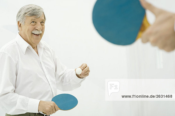 Senior man playing table tennis  hand holding paddle in foreground