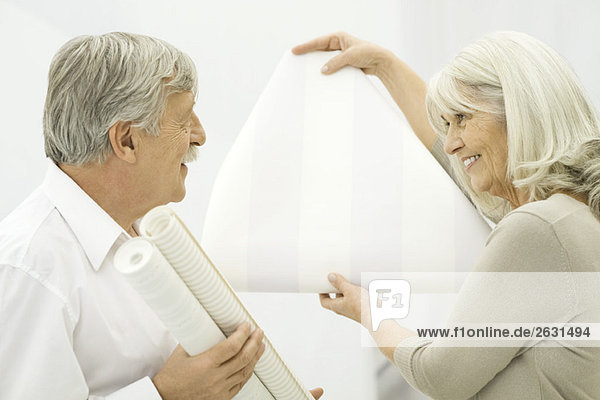 Senior woman showing wallpaper sample to senior man
