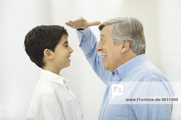 Grandfather comparing height with grandson  smiling at each other