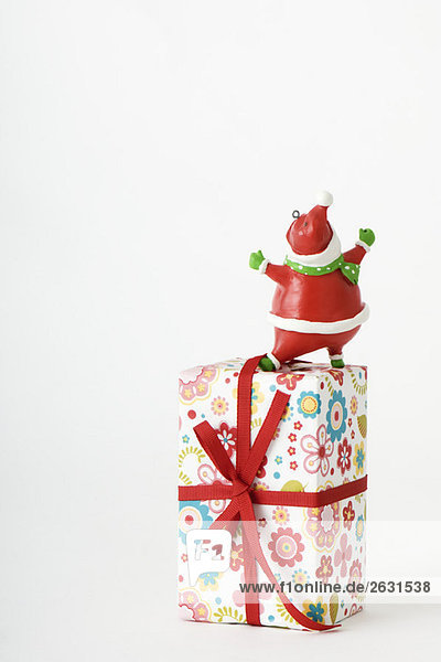 Santa Claus figurine standing on top of Christmas present