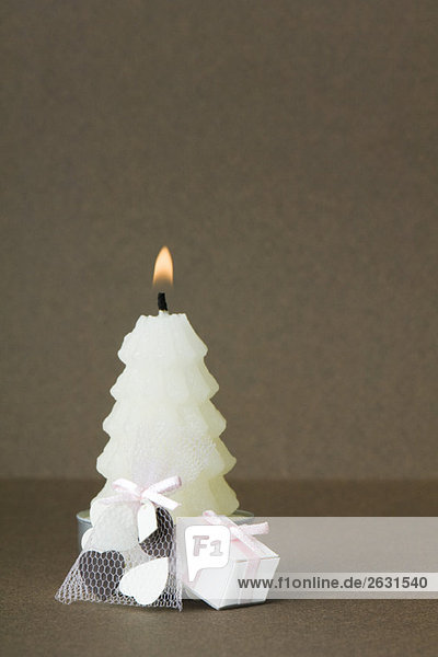 White Christmas tree shaped candle with miniature gifts set at base