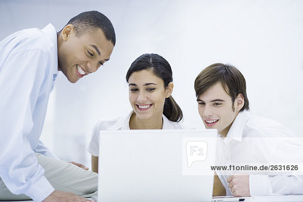 Young professionals looking at laptop computer together  smiling