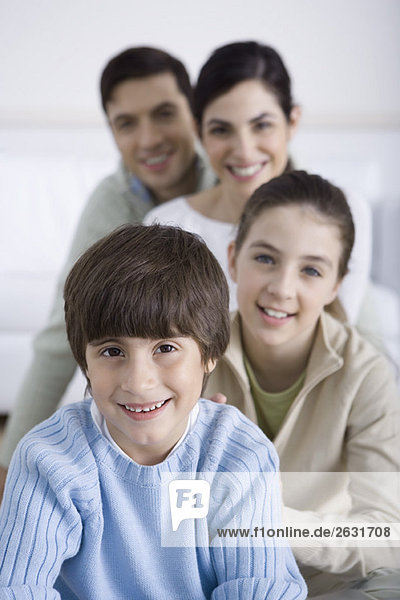 Junge sitzt mit seiner Familie hinter ihm  lächelnd  Porträt