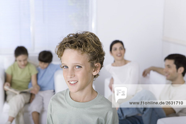 Junge lächelt in die Kamera  Familie entspannt im Hintergrund