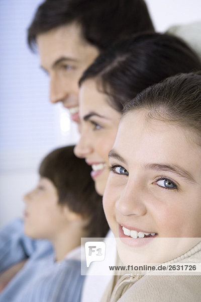 Girl sitting with family  smiling over shoulder at camera  close-up