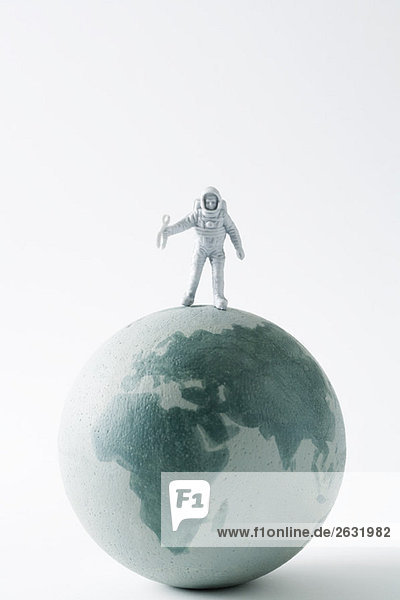 Miniatur-Astronaut auf dem Globus stehend