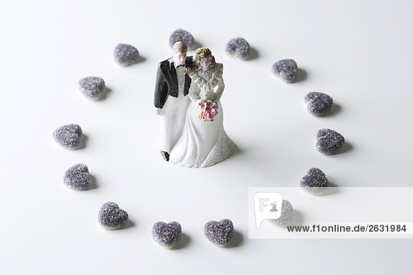 Miniaturbraut und Bräutigam umgeben von Süßigkeitenherzen