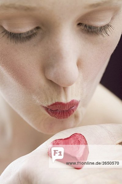 Junge Frau küsst rotes Schokoherz