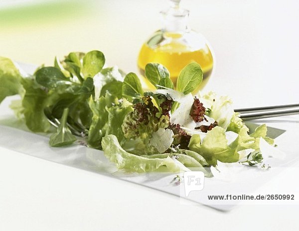 Gemischter Salat mit Parmesan  im Hintergrund Ölflasche