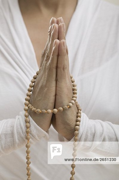 Junge Frau mit gefalteten Händen beim Meditieren