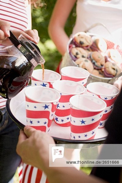 Frau giesst Kaffee in Pappbecher (4th of July USA)