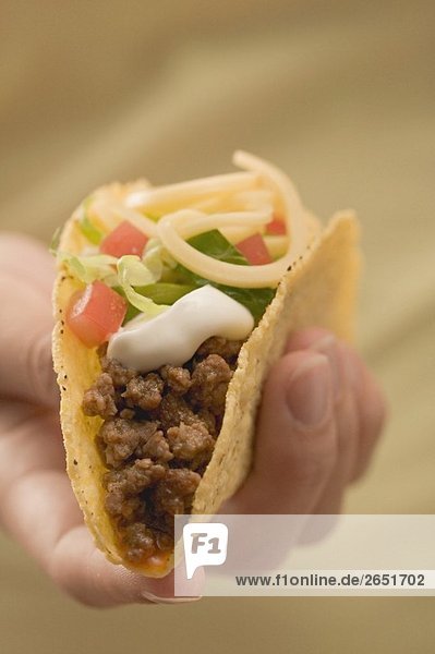 Hand hält Taco mit Hackfleisch und Käse