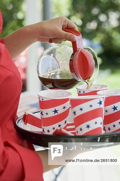 Frau giesst Kaffee in Pappbecher (4th of July  USA)