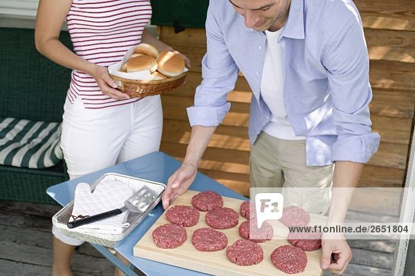 Mann bereitet Hamburger zum Grillen vor  Frau bringt Brötchen