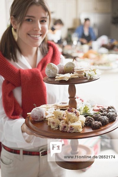 Young woman holding tiered stand full of Christmas fancies