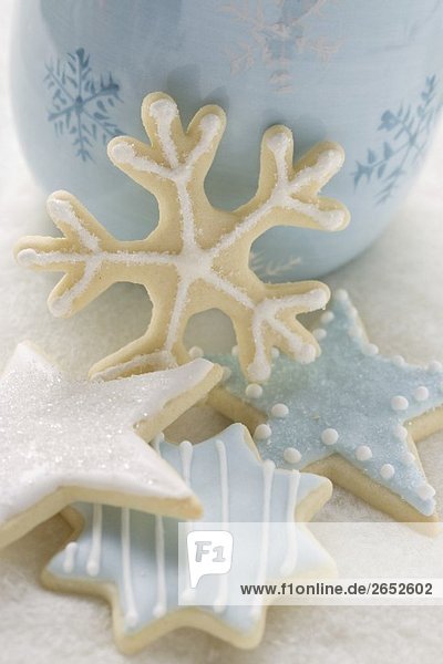 Weihnachtsplätzchen mit Zuckerglasur vor blauer Tasse