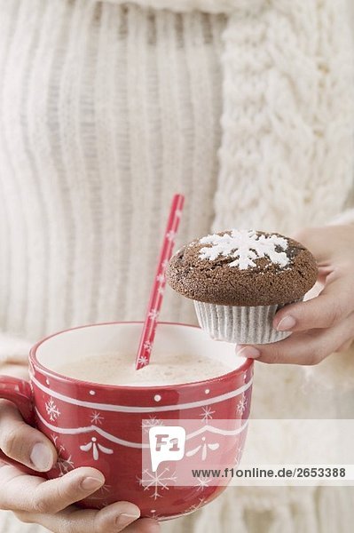 Frau hält Tasse Kakao und Schokoladenmuffin (weihnachtlich)