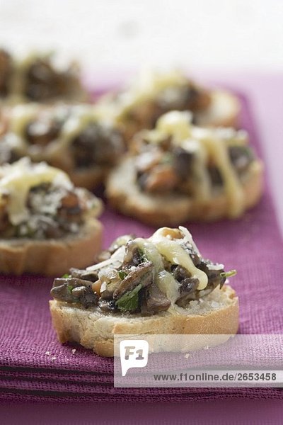 Überbackene Baguettescheiben mit Pilzen und Käse
