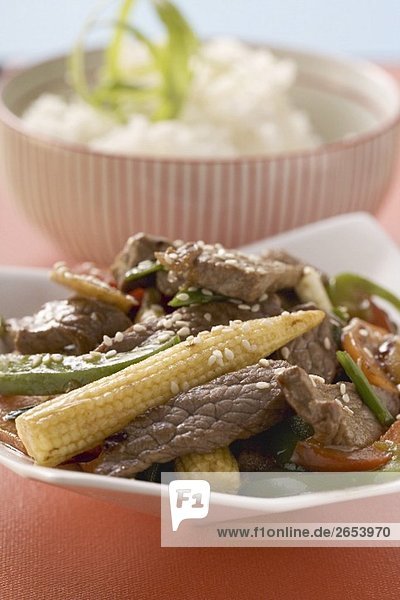 Rindfleisch mit Gemüse und Sesam  Reis im Hintergrund (Asien)