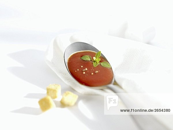 Ein Löffel Tomatensuppe  daneben Croutons
