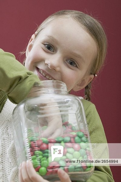 Kleines Mädchen nascht Schokolinsen aus Vorratsglas