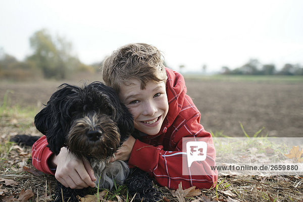 Portrait of boy hugging his dog and smiling