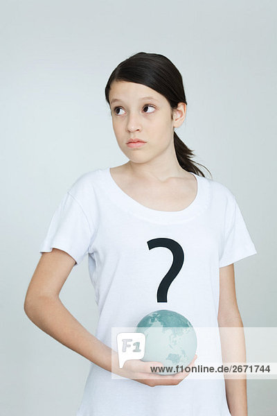 Mädchen im T-Shirt mit Fragezeichen bedruckt  Globus haltend  wegschauend